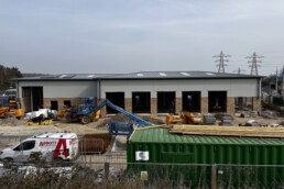 Current exterior construction progress of the whole building including the Formula One Autocentres unit, showing the modern structural framework and new cladding being installed on the commercial unit.