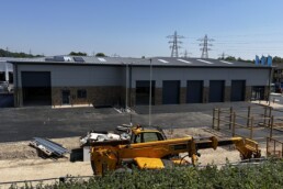 Current exterior construction progress of the whole building including the Formula One Autocentres unit, showing the modern structural framework and new cladding being installed on the commercial unit.