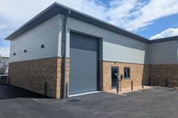 Completed exterior of Unit 2 at Broad Oak Business Park showing the installed roller shutter and glazed entrance.